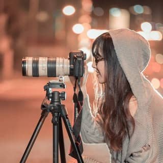 Photographe professionnelle utilisant un appareil posé sur un trépied de nuit